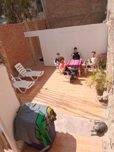 un groupe de personnes assises sur une terrasse en bois avec des chaises dans l'établissement La Petite Maison, à Nazca