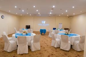 a room with white tables and chairs with blue tablecloths at Hotel Hillview Islamabad in Islamabad