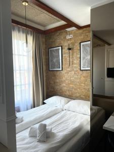 a bedroom with a white bed with a brick wall at Hotel Zlatni Bor in Sokolac