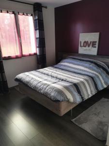 een bed zittend in een slaapkamer met een bord dat liefde zegt bij La maison de Marie 