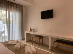 een slaapkamer met een tv aan de muur en handdoeken bij Ladiko Inn Hotel Faliraki -Anthony Quinn Bay in Faliraki