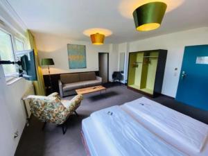 een slaapkamer met een bed, een bank en een tafel bij Hotel Christina in Keulen