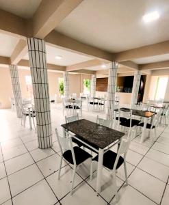 a dining room with tables and white chairs at Hotel Aconchego Cearense in Fortaleza