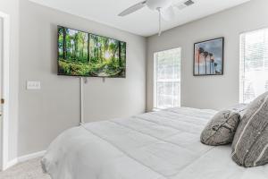 a white bedroom with a bed and a tv on the wall at Lowcountry haven - game rm + king bds, mins 2 dwtn in Charleston