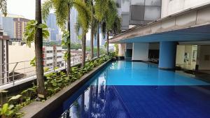 a swimming pool on the roof of a building with palm trees at One Maxim Residence at Taragon in Kuala Lumpur