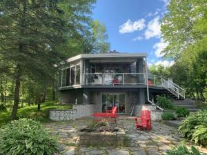 a large house with a balcony and red chairs at Waterfront Cottage in Muskoka in Severn