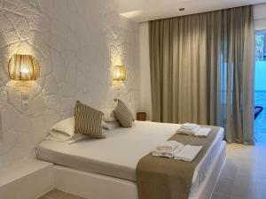 a white bedroom with two beds and a window at Ladiko Inn Hotel Faliraki -Anthony Quinn Bay in Faliraki