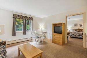 Una sala de estar con una mesa y sillas y un televisor. en Cedarbrook Deluxe one bedroom suite located on 2nd floor with outdoor heated pool 21820, en Killington