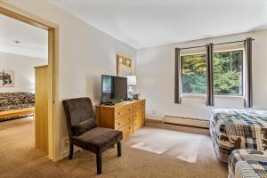 Un dormitorio con una cama y una silla y un televisor. en Cedarbrook Deluxe one bedroom suite located on 2nd floor with outdoor heated pool 21820, en Killington