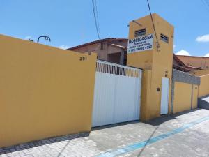 uma casa amarela com uma cerca branca e uma garagem em Pousada Encontro das águas em Fortaleza