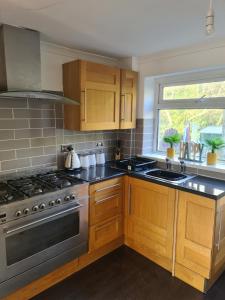 La cuisine est équipée de placards en bois et d'un four avec plaques de cuisson. dans l'établissement Guest house room 1, à Haverfordwest