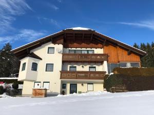 a large house with a wooden roof in the snow at Ferienwohnung Pyhrgasblick in Rosenau am Hengstpass