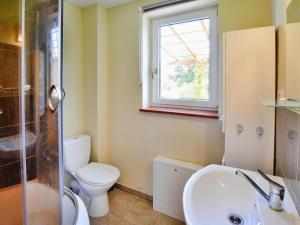 a bathroom with a toilet and a sink and a window at Lakeside holiday home, private garden in Dąbrowica +21 photos
