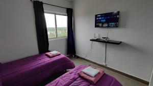 a room with two beds and a window with purple sheets at Cavas de Mendoza - Syrah - 3 habitaciones - Frente al Shopping in Guaymallen