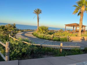 a path with palm trees and a gazebo and the ocean at Apartamento del Toyo in Almería