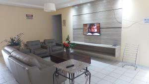 sala de estar con sofá y TV en la pared en Gurgueia Palace Hotel, en Bom Jesus