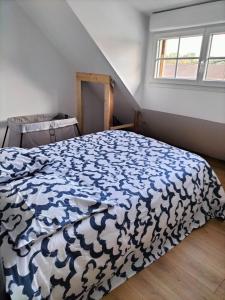 um quarto com uma cama com um edredão azul e branco em Maison du petit p(a)in em Cucq
