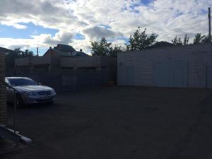 a car parked in a parking lot next to a fence at Altyn Adam Hotel in Pavlodar