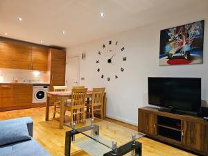 uma sala de estar com uma mesa e um relógio na parede em Cozy Flat close to central London em Londres