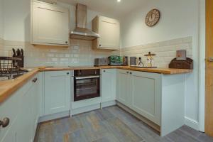 a kitchen with white cabinets and a clock on the wall at Branlea - In the Heart of Ludlow in Ludlow