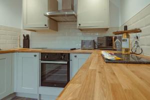 uma cozinha com armários brancos e um balcão de madeira em Branlea - In the Heart of Ludlow em Ludlow