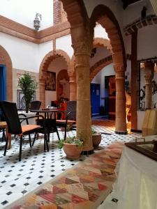 um quarto com arcos, mesas e cadeiras em Riad Zawia em Essaouira