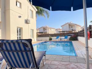 阿依納帕的住宿－Sunset Pearl Holiday Villa，游泳池旁的椅子和遮阳伞