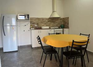 y cocina con mesa, sillas y nevera. en Complejo “Aloe Vera” en Villa Dolores