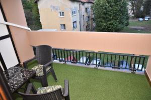 uma varanda com cadeiras e um relvado verde em ENA apartman em Kraljevo