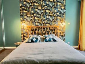 łóżko z 2 poduszkami w sypialni z tapetą w obiekcie Maison au calme 2 Chambres Terrasse Clim parking gratuit w Montpellier