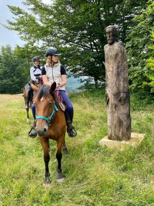 dos personas montando a caballo junto a una estatua en Eco Lodge Taor en Taor
