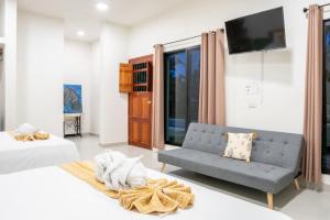 a room with two beds and a couch and a tv at Hotel Makech in Bacalar