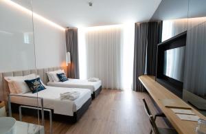 a hotel room with two beds and a flat screen tv at Empire Beach Resort ADULTS ONLY in Dhërmi