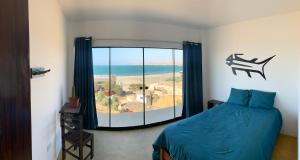 a bedroom with a bed and a large window at Tayta Surf House in Lobitos