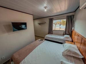 a small bedroom with two beds and a window at Pousada Porto Girassol in Abraão