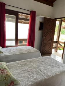 una camera con due letti e una porta e finestre di Green house a Praia do Rosa