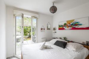 1 dormitorio con cama blanca y ventana grande en Bright duplex with terrace in Nanterre - Welkeys, en Nanterre