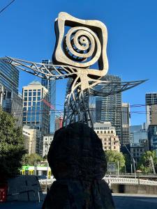 een metalen standbeeld met een spiraal erop in een stad bij Prima Tower in Melbourne