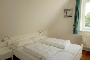 a white bed in a room with a window at Ferienhaus "SonnenInsel Fehmarn" 9015 - Fehmarn in Fehmarn
