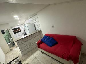 Il comprend une petite chambre avec un lit rouge et une cuisine. dans l'établissement Casa baixinha, à Ubajara