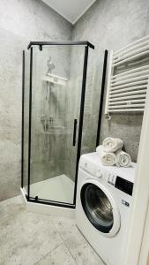 y baño con ducha y lavadora. en JM Millennium Kawęczyńska 37, en Varsovia