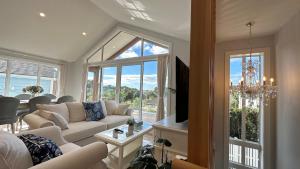 een woonkamer met een bank en een tv bij Stunning Rothesay Bay in Auckland