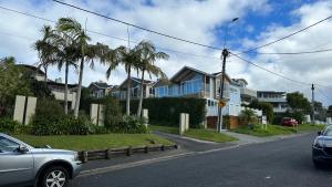 a street with houses and a car parked on the road at Stunning Rothesay Bay in Auckland