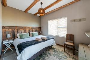 a bedroom with a large bed and a chair at Dennehof Farm Guesthouse in Villiersdorp