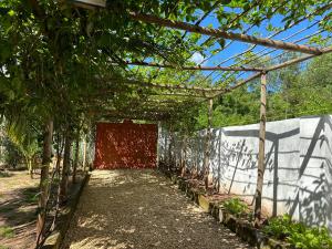 a garden tunnel with a red wall and trees at Cozy private villa in Fukuchani in Mchangani