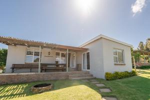 a white house with a bench in the yard at Dennehof Farm Guesthouse in Villiersdorp