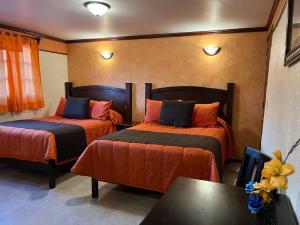 1 dormitorio con 2 camas de color naranja y azul en Hotel Paraiso Real Plus en Mineral del Monte