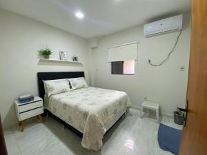 um pequeno quarto com uma cama e ar condicionado em Agradable dormitorio en suite con estacionamiento privado em Ciudad del Este