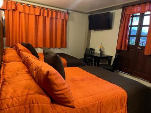 ein Schlafzimmer mit zwei Betten mit orangefarbener Bettwäsche und einem Fenster in der Unterkunft Hotel Paraiso Real Plus in Mineral del Monte