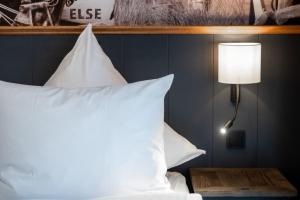 um quarto com uma cama com almofadas brancas e um candeeiro em 4Hafenzeiten - Ferienwohnung NIE 4 Else em Timmendorfer Strand